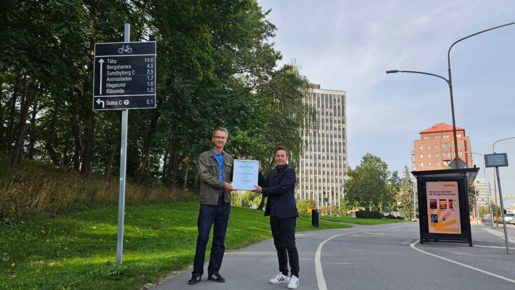 Miljöpartiets kommunalråd Bernhard Huber tar emot ett diplom där Solna stad utsetts till "Grönt föredöme" från Gröna mobilisters ordförande Jesper Johansson på en cykelväg utanför Solna stadshus